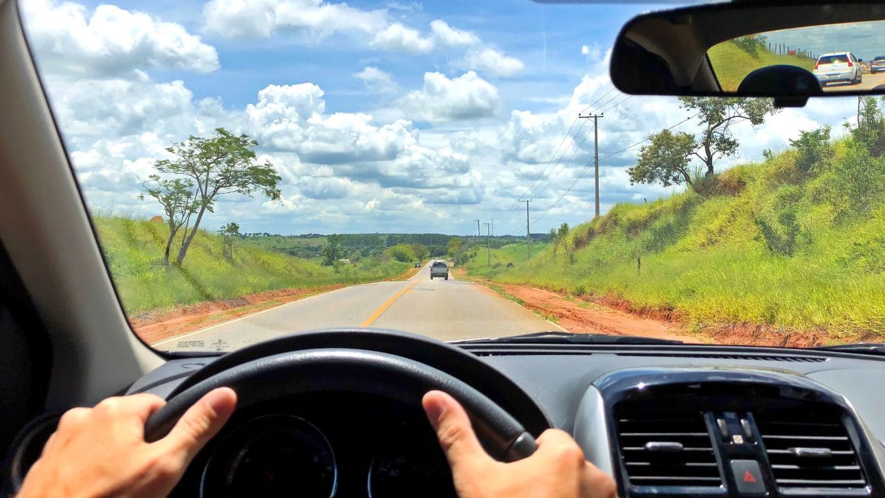 Motorista profissional dirige com atenção em estrada longa e ensolarada no Brasil.