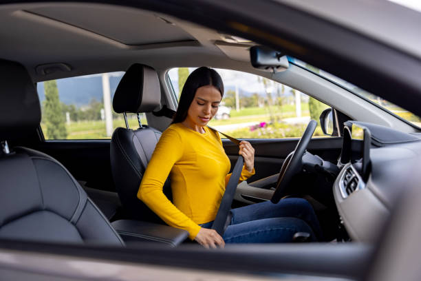 Mulher sentada em seu carro e afivelando o cinto de segurança - conceitos de meio de transporte